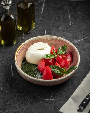 Seramik kasede burrata, domates ve fesleğen yapraklı taze Caprese salatası.