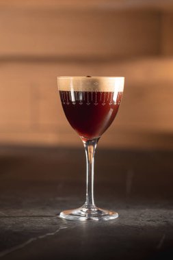 Zarif bardakta espresso martini kokteyli ve koyu fonda kahve çekirdekleri.