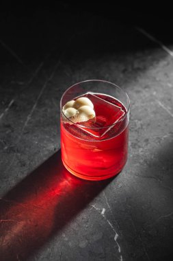 Beyaz çikolatalı ve büyük buzlu şık kırmızı kokteyl. Bardakta servis ediliyor. Koyu taştan arka planda dramatik bir ışık.