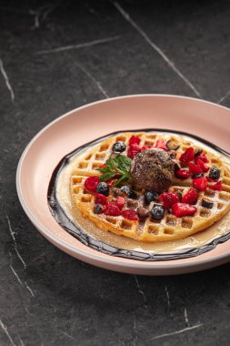 Çikolatalı dondurmalı waffle ve pembe tabakta taze böğürtlen.
