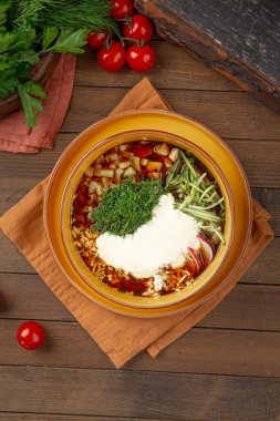 Kvass sebzeli Okroshka çorbası ve sarı kasede otlar.