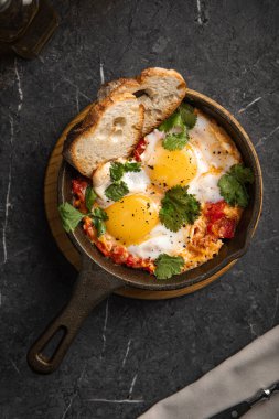 Bitkilerle taze pişmiş yumurtalar ve tost karanlık bir taş masada küçük bir tavada servis ediliyor.