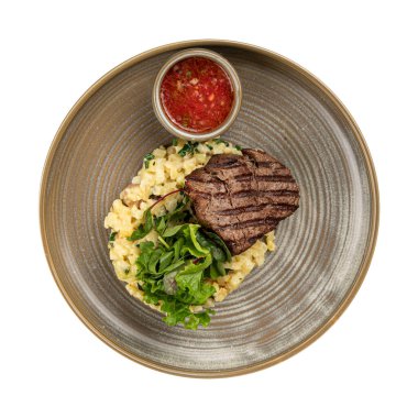 Izgara biftek, yanında patates püresi ve domates sosu.