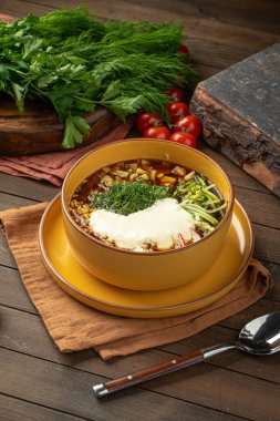 Kvass sebzeli Okroshka çorbası ve sarı kasede otlar.