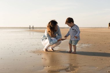 Sahilde yürümeye başlayan çocuk ile keşfetmek Genç Anne