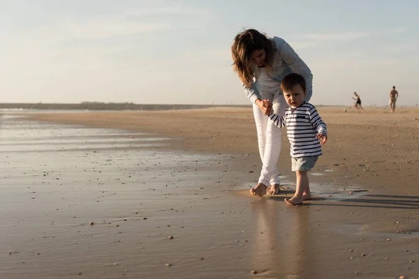 若い母親は幼児とビーチを散策 — ストック写真