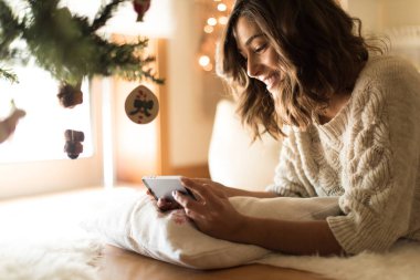 Bir akıllı telefon kullanan kadın evde - kış ve Noel sezonu