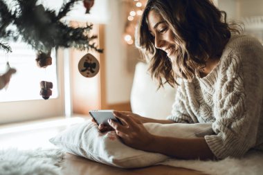 Bir akıllı telefon kullanan kadın evde - kış ve Noel sezonu