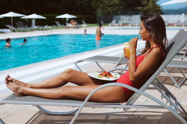 在泳池边吃新鲜沙拉和喝果汁的妇女 — 图库照片