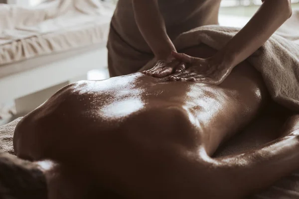 Man Met Een Rug Massage Met Olie Warme Stenen — Stockfoto