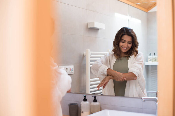 Beautiful woman in the bathroom  moisturizing her skin 
