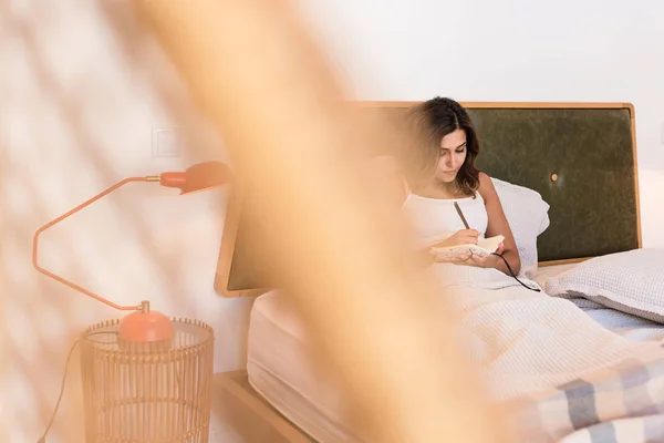 Mulher na cama escrevendo em seu diário — Fotografia de Stock