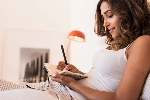 Woman in the bed writting on her diary — Stock Photo, Image