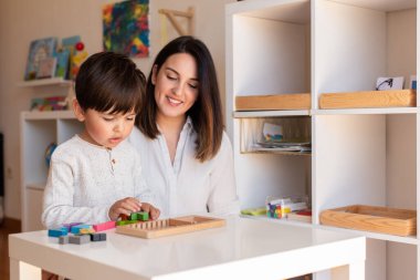 Lillte Kid tetris tahtası bulmacasıyla oynuyor ve annesi ya da öğretmeni yardım ediyor. Ev hapsi. Öğrenme Topluluğu. Montessori Schoo