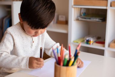 Küçük kreş çocuğu renkli kalemlerle resim çiziyor. Evde eğitim. Öğrenme topluluğu. Montessori Okulu. 
