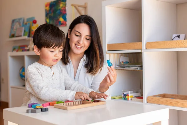 小不点小子在玩小提琴手的木头拼图和妈妈或老师的帮助 在家做家务 学习社区 Montessori Schoo — 图库照片