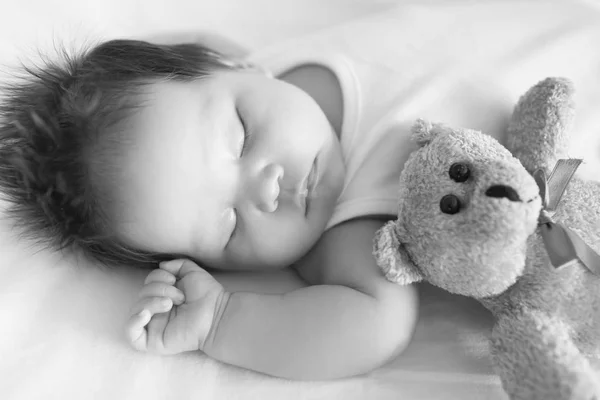 可爱的宝宝 在旁边一只泰迪熊在一个凉爽的下午 在黑色和白色的小床里安静地睡着 — 图库照片