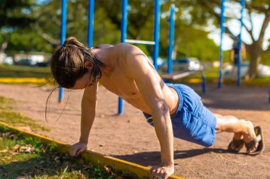 Parkta açık spor salonunda egzersiz uygun bir adam. İşin push up.