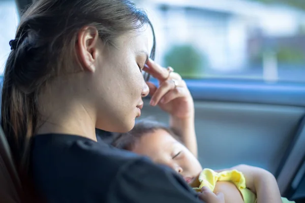 Portretul unei mame stresate care încearcă să facă față în timp ce își poartă copilul adormit în brațe — Fotografie, imagine de stoc