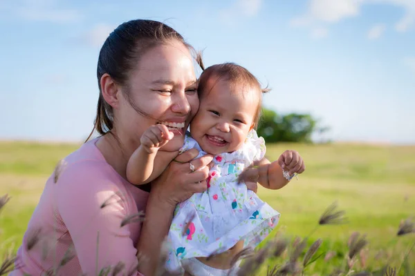 Anne ve kızı açık eğleniyor. Oyun ve birlikte parkta gülüyor aile. Güneşli bir günde yeşil alana oturan. — Stok fotoğraf