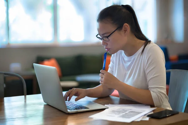 Uma jovem mulher fazendo trabalho em seu computador portátil em casa . — Fotografia de Stock