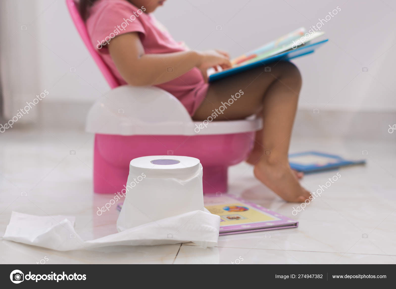 Toddler potty training. reading books on the toilet. Stock Photo by