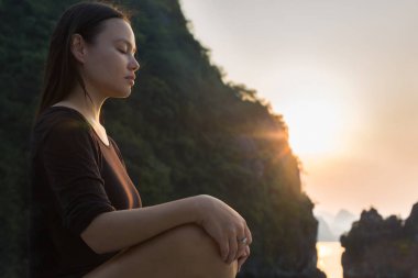 Gün batımında dinlenen ve meditasyon yapan bir kadın. Huzurlu zen.