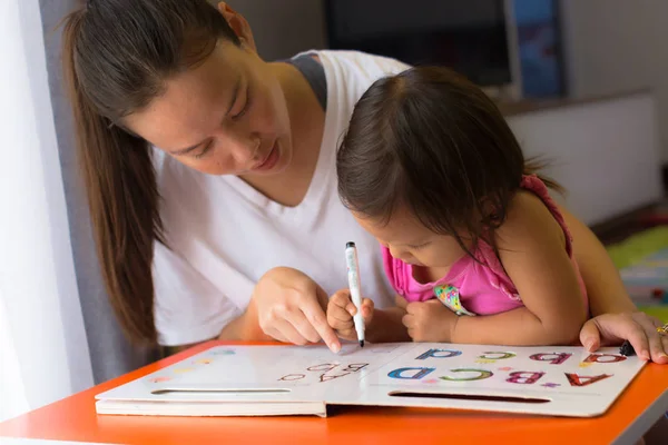 Egy anya tanítása gyermeke, hogyan kell írni a ábécék. könyveit koncepció. Gyerekek összpontosítása és koncentrálása. — Stock Fotó