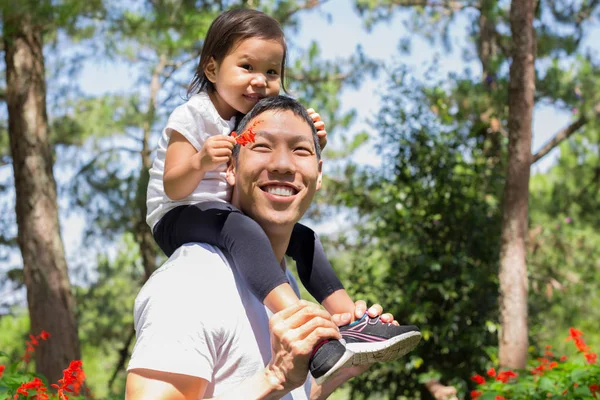 Feliz pai e criança rindo e brincando juntos, cuidando filha de costas em um parque florestal ao ar livre — Fotografia de Stock