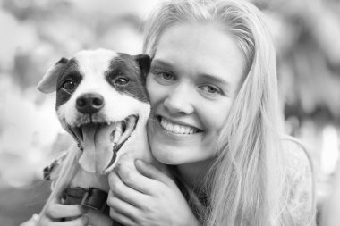 Köpeğine sarılan, açık hava parkında oynayan bir kadın..