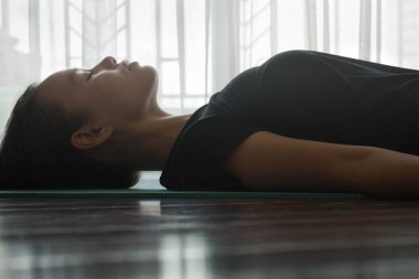 Genç bir kadın yoga minderinde gözleri kapalı meditasyon yapıyor.