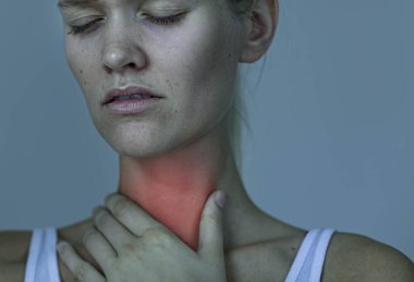 Bölgeyi elinde tutan genç bir kızın boğaz ağrısının izole edilmiş kırmızı noktası.