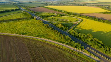 İnsansız hava aracı manzaralı güzel bir kır manzarası. Arazinin ortasındaki yolun havadan çekilmiş fotoğrafı. Yaz güneşli bir günde otobanın üzerinden uçar.