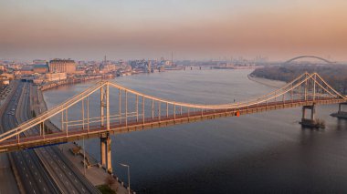 Kyiv şehrindeki Dnipro nehri üzerindeki yaya parkı köprüsünün havadan görüntüsü. Gün doğumunda şehir manzarası. Kiev, Ukrayna
