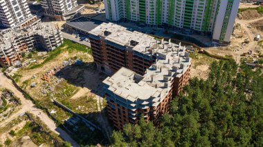 Gökdelen yapısının inşaat sürecinin görüntüleri. Çok katlı modern apartmanın havadan aşağıya fotoğrafı. Yeşil ağaçlar arasında kentsel binaların inşası.
