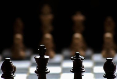 Yukarı dönük olacak şekilde bir satranç tahtası üzerinde siyah ve beyaz satranç figürleri