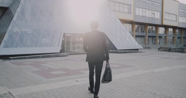 Un bell'uomo d'affari viene al lavoro la mattina con la valigetta in mano. . — Video Stock