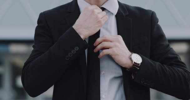 Молодой бизнесмен крупным планом организует галстук перед камерой — стоковое видео