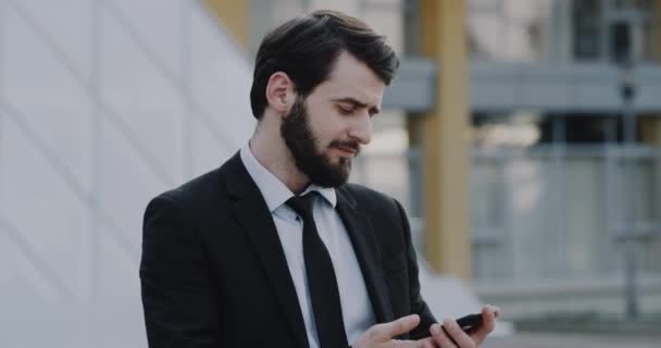 Charismatischer Mann im Anzug telefoniert vor Geschäftsbüro — Stockvideo