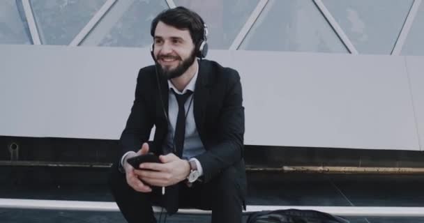 Joven Feliz Traje Escuchando Musicar Usando Los Auriculares Sentado Lado — Vídeo de stock