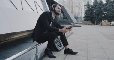 Oldukça genç adam iş merkezi oturarak bir kulaklık ile müzik dinleme