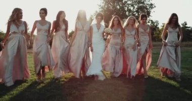 Nedime ve muhteşem gün batımı arka plan ile çimenlerin üzerinde yürüyüş güzel gelin. Kırmızı destan. 4k