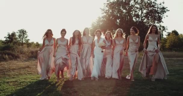 Incroyable belle mariée avec ses filles d'équipe avec des robes de style boho marchant dans un coucher de soleil incroyable. Motions lentes — Video