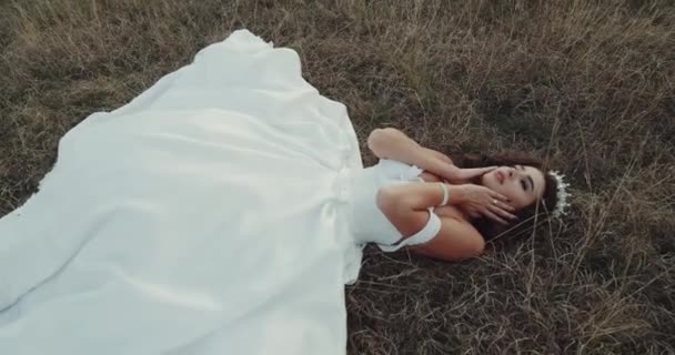 Hermosa novia con vestido increíble acostado en la hierba . — Vídeo de stock