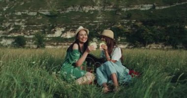 Genç ve güzel kızlar ve sağlıklı sebze sandviç yeme ve kameraya bakarak gülen piknik zamanı var. 4k