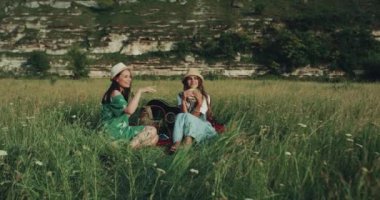 İki kız manzara, ortasında sandviç yeme ve uzak bir yere bakarak piknik