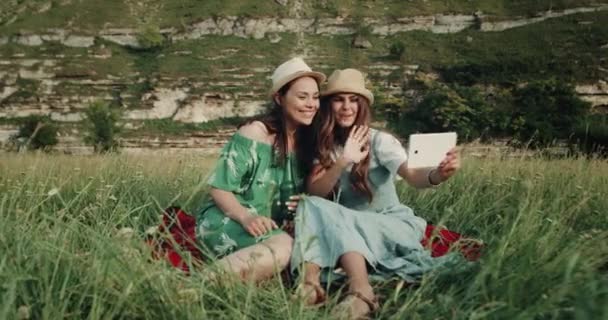 Chicas pasar un buen tiempo juntos en el picnic, y tener una conversación encantadora usando la tableta — Vídeo de stock