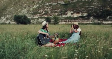 İki kız Dağları ile inanılmaz yer piknik, gitar ve şaşırtıcı fotoğraf çekimi şarkı söylüyorlar. yavaş hareketleri
