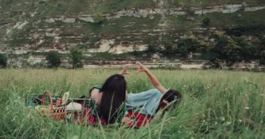 Çok gülümseyen kız piknikte birlikte oynayan ve kalp el ile yapma.