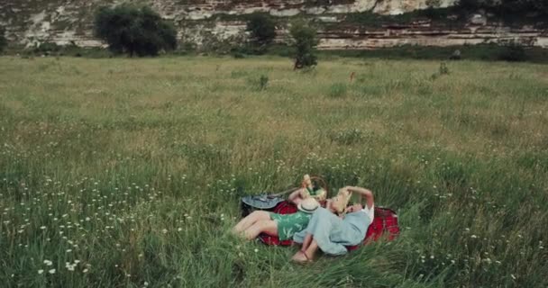 Dos chicas tumbadas en la manta en medio de la naturaleza y vomitando los sombreros . — Vídeos de Stock